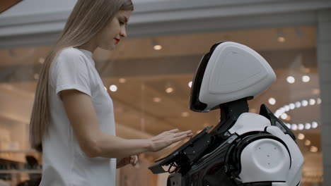 A-female-programmer-tests-the-robot-for-the-ability-to-interact-with-users.-The-use-of-a-robot-assistant-in-the-office.-The-robot-gives-help-to-the-girl